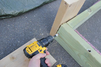 En hånd skrur fast solide skruer med en gul drill. 