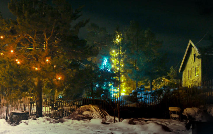 Julelys i flere farger kaster lys mot husfasaden.