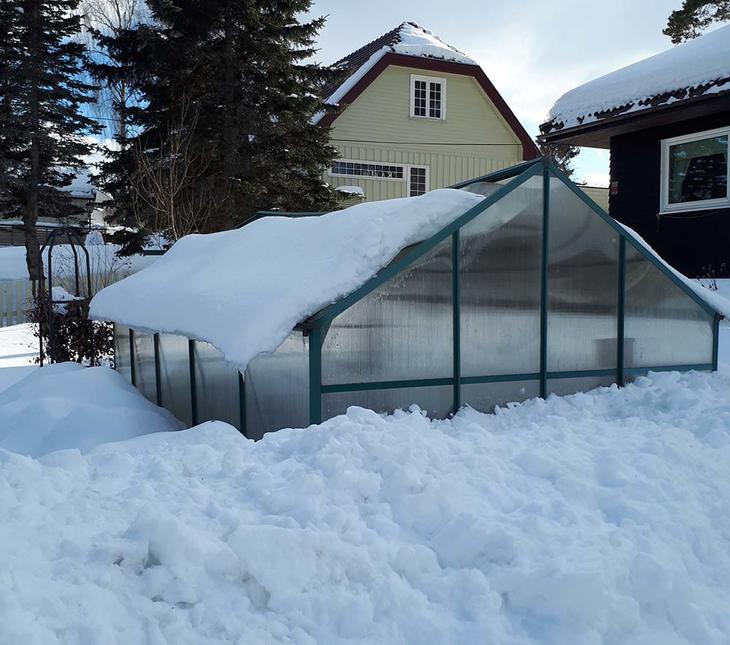 Et hobbydrivhus begravd i tung snø. 