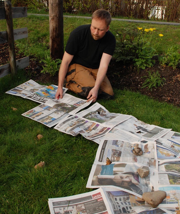En mann sprer aviser utover et område med gress
