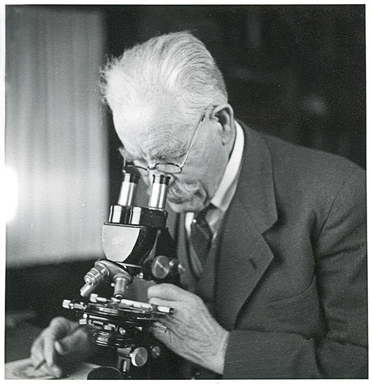 Forskeren Emil Korsmo avbildet mens han kikker ned i et mikroskop. 